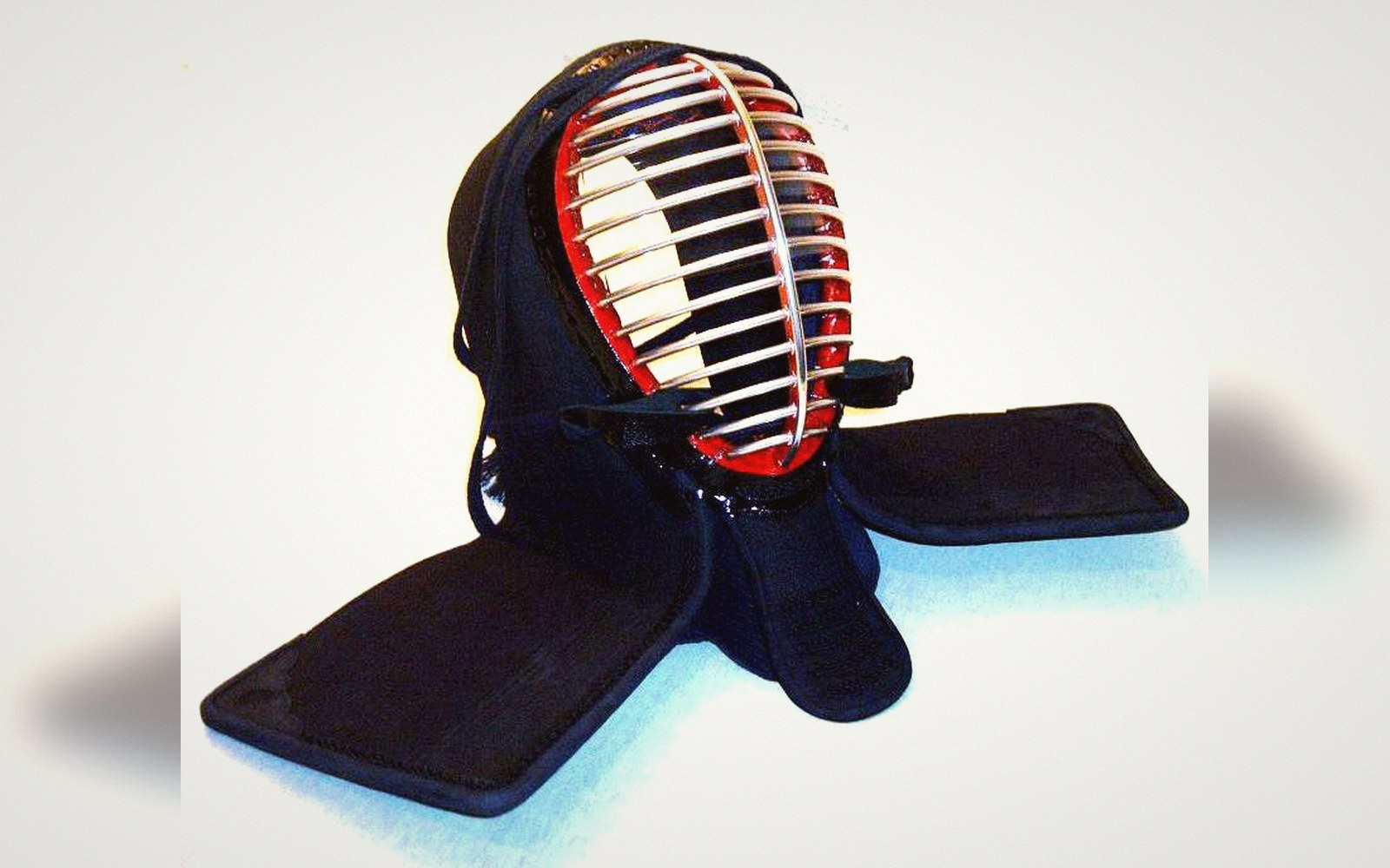 A kendo men helmet with metal grille, padded flaps and red-lined interior